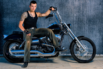 Fototapeta na wymiar Tough, tattooed fighter with his bike in chopper-style