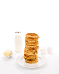 Pile of pancakes with ingredients in background.