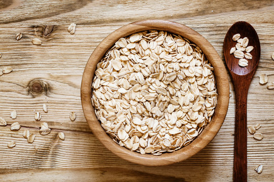 Oat flakes in a round bowl on the old wooden background, top vie