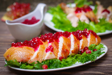 roasted baked chicken breast with cranberry and pomegranate sauce in a gravy boat on a wooden table