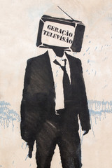 View of a graffiti of a man on suit with a television instead of it's head, with the words...