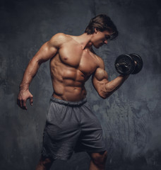 Shirtless muscular man holding a dumbbell.