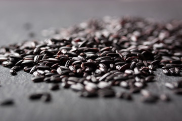 Black rice on a dark stone background with copy space, selective focus.
