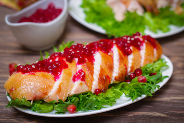 roasted baked chicken breast with cranberry and pomegranate sauce in a gravy boat on a wooden table