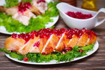roasted baked chicken breast with cranberry and pomegranate sauce in a gravy boat on a wooden table