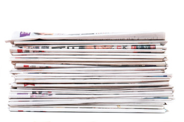 View of a pile of newspapers stacked isolated on a white background.