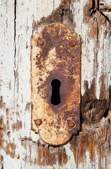closeup of old rusty keyhole decorative element on weathered wooden surface