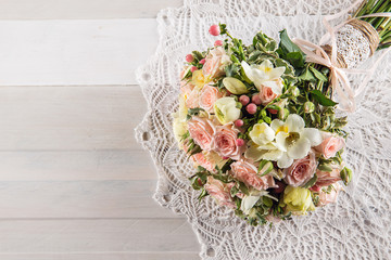 Beautiful wedding bouquet of roses and freesia on white wooden background, background for...