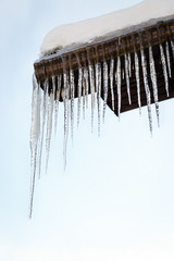 Icicles on the roof. Winter concept. Blue Sky background.