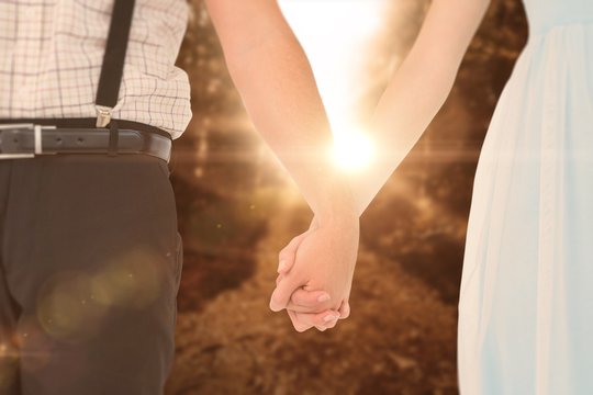 Composite image of hipster couple standing hand in hand 