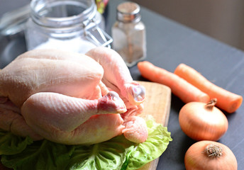 Raw chicken with vegetables on black background