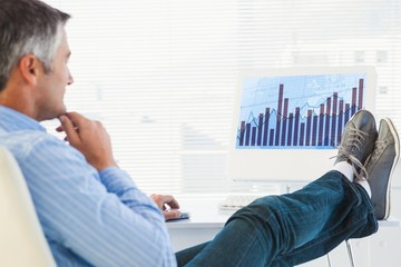 Composite image of relaxed man with feet on desk using computer