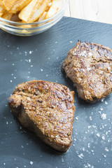 cooked beef chateaubriand steak with chunk chipped potatoes on p