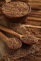 Buckwheat seeds in wooden spoon on a brown wooden table