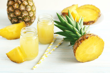 Fototapeta na wymiar Bottles of pineapple juice on a white wooden table