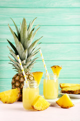 Bottles of pineapple juice on a pink wooden table