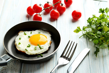 Fried eggs in pan on blue wooden table