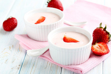Strawberry yogurt in bowl on a blue wooden table