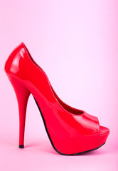 Red patent leather high-heeled shoes on a pink background