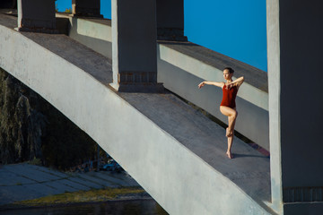 Young beautiful woman gymnast posing on bridge girder