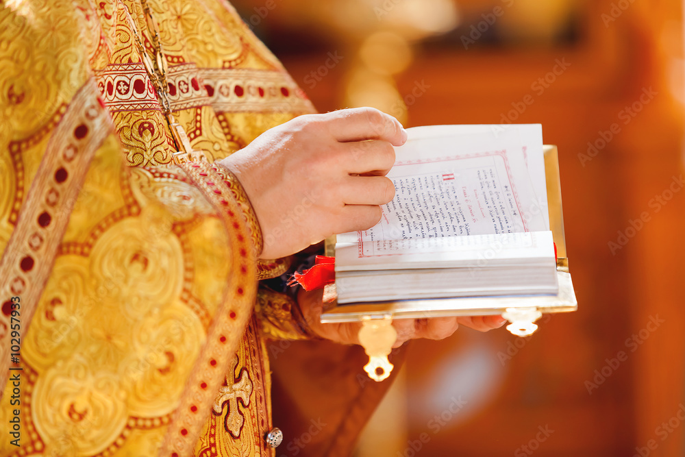 Wall mural Prayer book in the hands of the priest. Ceremony in the Orthodox Christian Church. Russia.