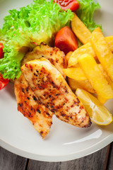 Grilled chicken breasts served with fries and fresh salad