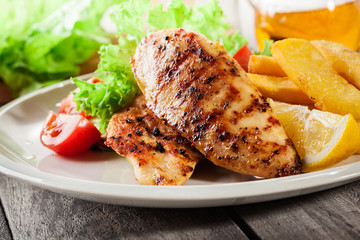Grilled chicken breasts served with fries and fresh salad
