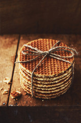 Pile of stroop waffles with jute bow with empty space on dark brown background