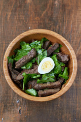 Bowl of fried liver with quail egg, top view