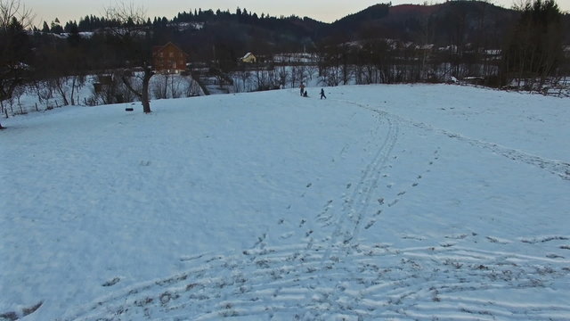 Father pulling slade and kids having fun in winter, aerial view