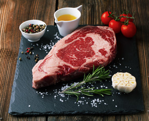 Raw ribeye steak marbled meat with salt, rosemary and garlic