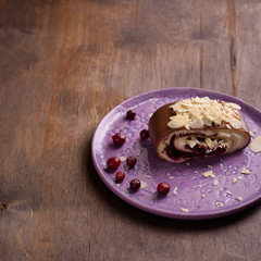 Chocolate and almond cake with cranberry on wooden background.
