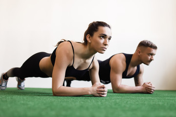 Fototapeta na wymiar Man and woman doing plank exercises at the gym