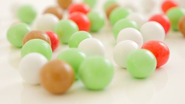 Colorful button-shaped candies on white reflective surface 4K 2160p UltraHD footage - Colorful round bonbons on white background slow tilting 4K 3840X2160 UHD video 
