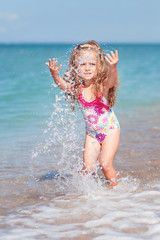 Fototapeta premium happy girl on a beach has a fun with splash