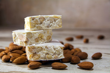 Torrone or nougat and almonds on a rustic wooden table, close up