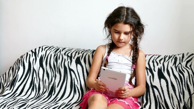 teen girl  playing tablet game sitting on bed