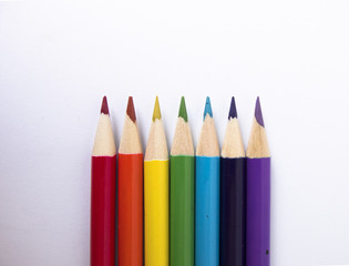 Rainbow of colored pencils, white background, view from the top