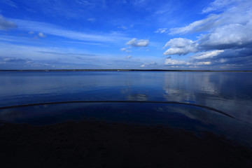 Lustrzane odbicie chmur i błękitnego nieba w jeziorze.
