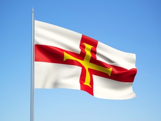 Guernsey 3d flag floating in the wind with a blue sky background 