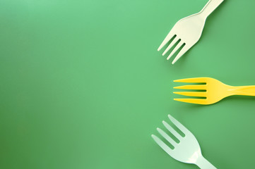 White and yellow plastic forks appearing to come together on a green background