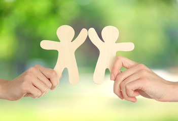 Hands with wooden mens on green nature background. Friendship, ecology or teamwork concept
