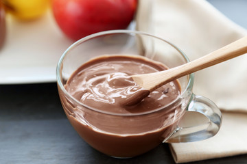 Melted chocolate in bowl, on wooden background