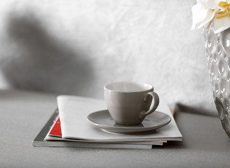 Cup of coffee and beautiful orchid flowers in the vase on kitchen table, close up