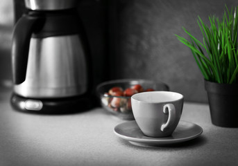 Cup and coffee machine on the kitchen table, close up