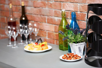 Wine bottles and canape on the kitchen table against a brick wall