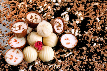 Assorted chocolate candies with flakes on black background