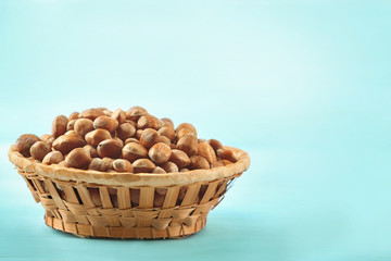 Hazelnuts in wicker basket on color wooden background