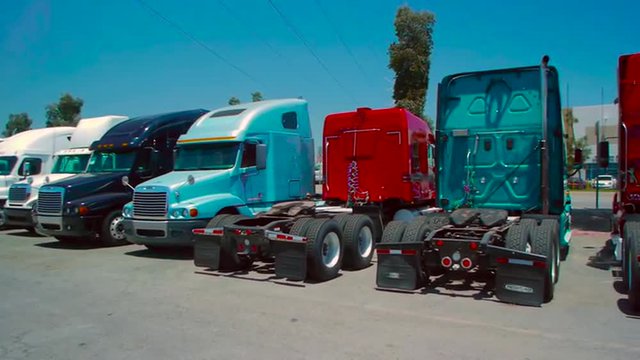 Slow pan of freight liner trucks parked in an outdoor lot