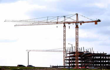 Construction site with red cranes on blue sky background